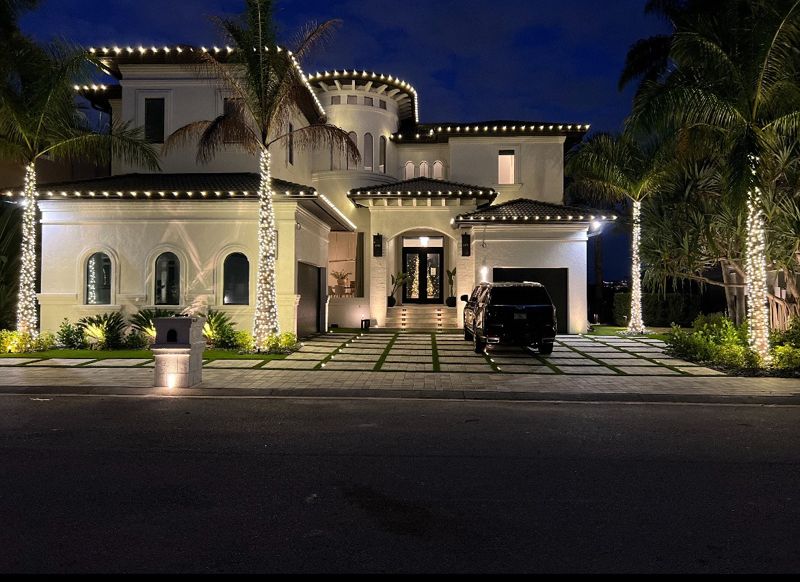 Large estate home with roofline lights and wrapped palm trees