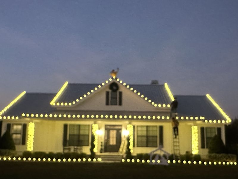 Ranch home with roofline lights and a lit wreath over the front door